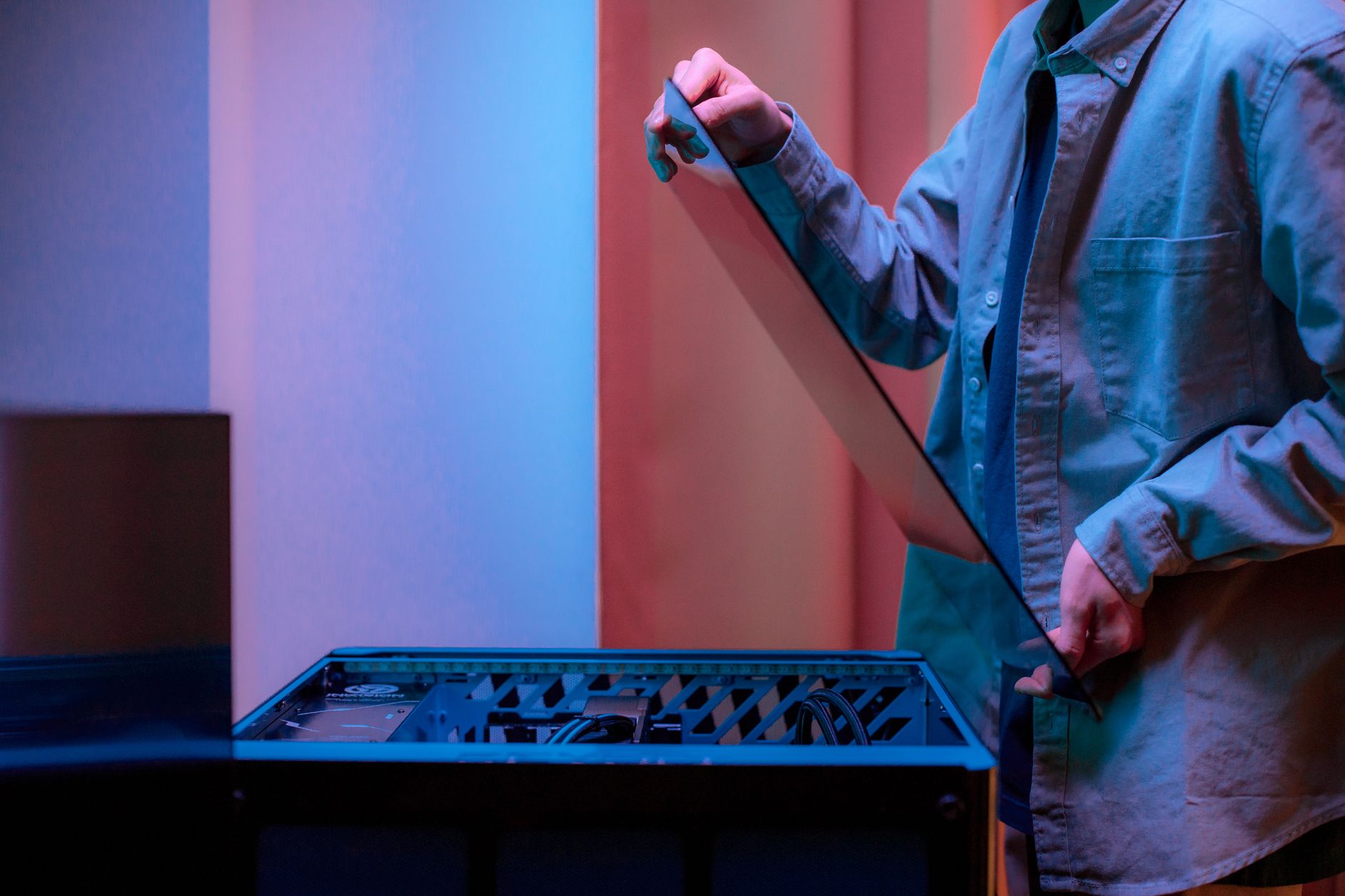 A man carefully fits a glass panel onto a gaming PC while adjusting internal cables.