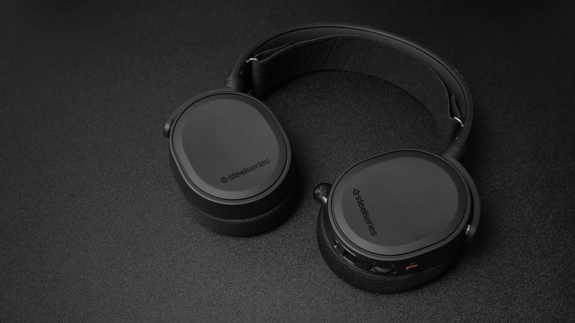 Close-up of SteelSeries headphones on a black surface. Minimalist and sleek.
