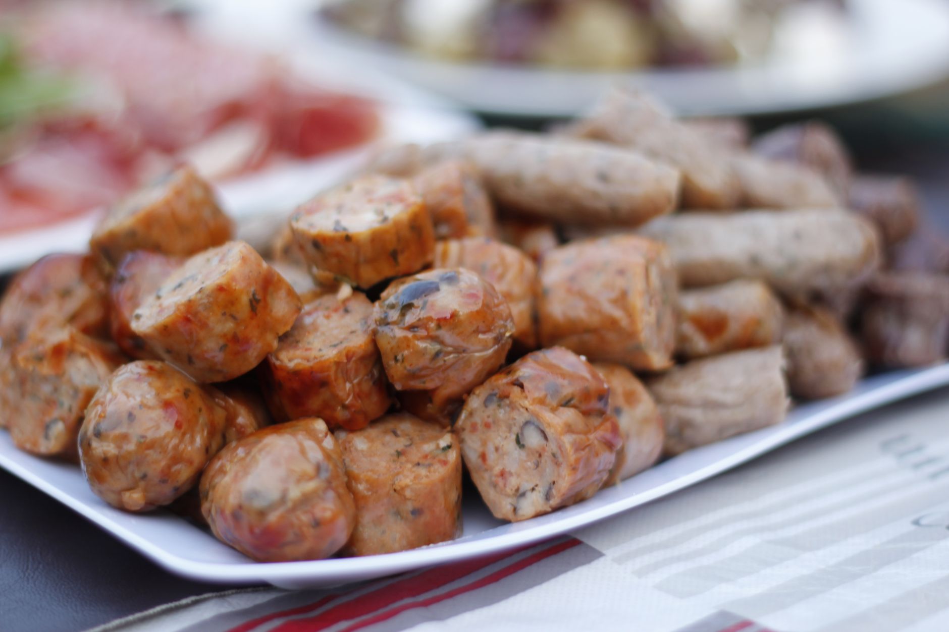 Close-up of cooked sliced sausages on a white plate, tempting and delicious.