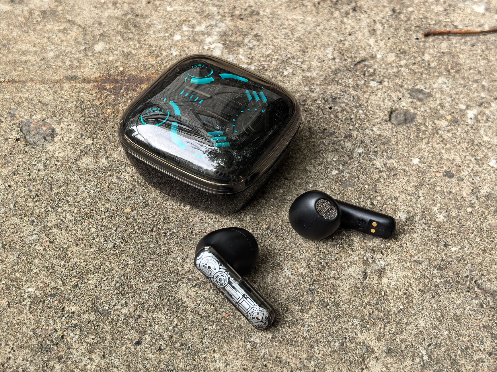 Close-up of sleek wireless earbuds with case on a concrete ground, outdoors.
