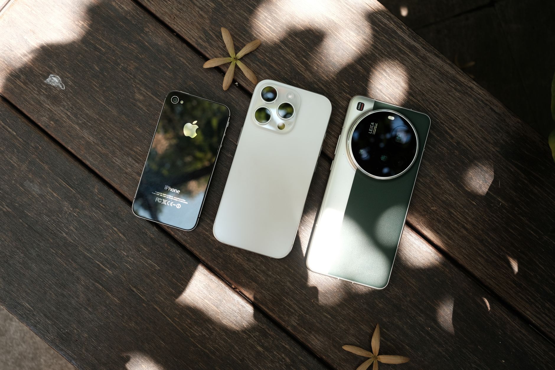 Three modern smartphones displayed on a wooden surface with natural lighting.