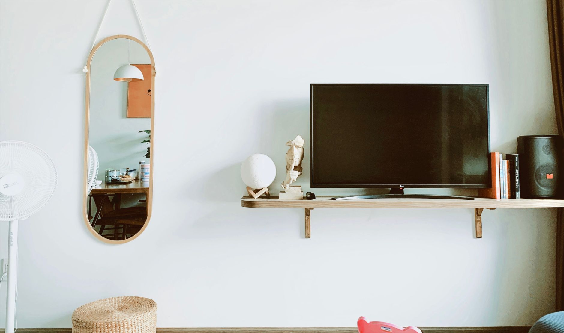 Stylish living room featuring a wall-mounted TV, a mirror, and modern decor on a white wall.