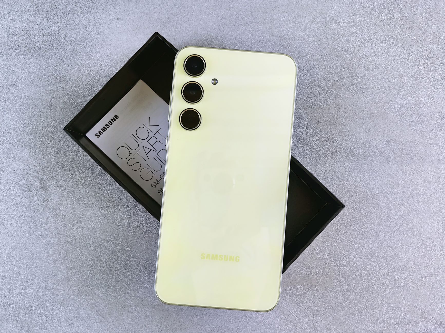 Stylish yellow smartphone featuring triple camera design and logo against a sleek box packaging.
