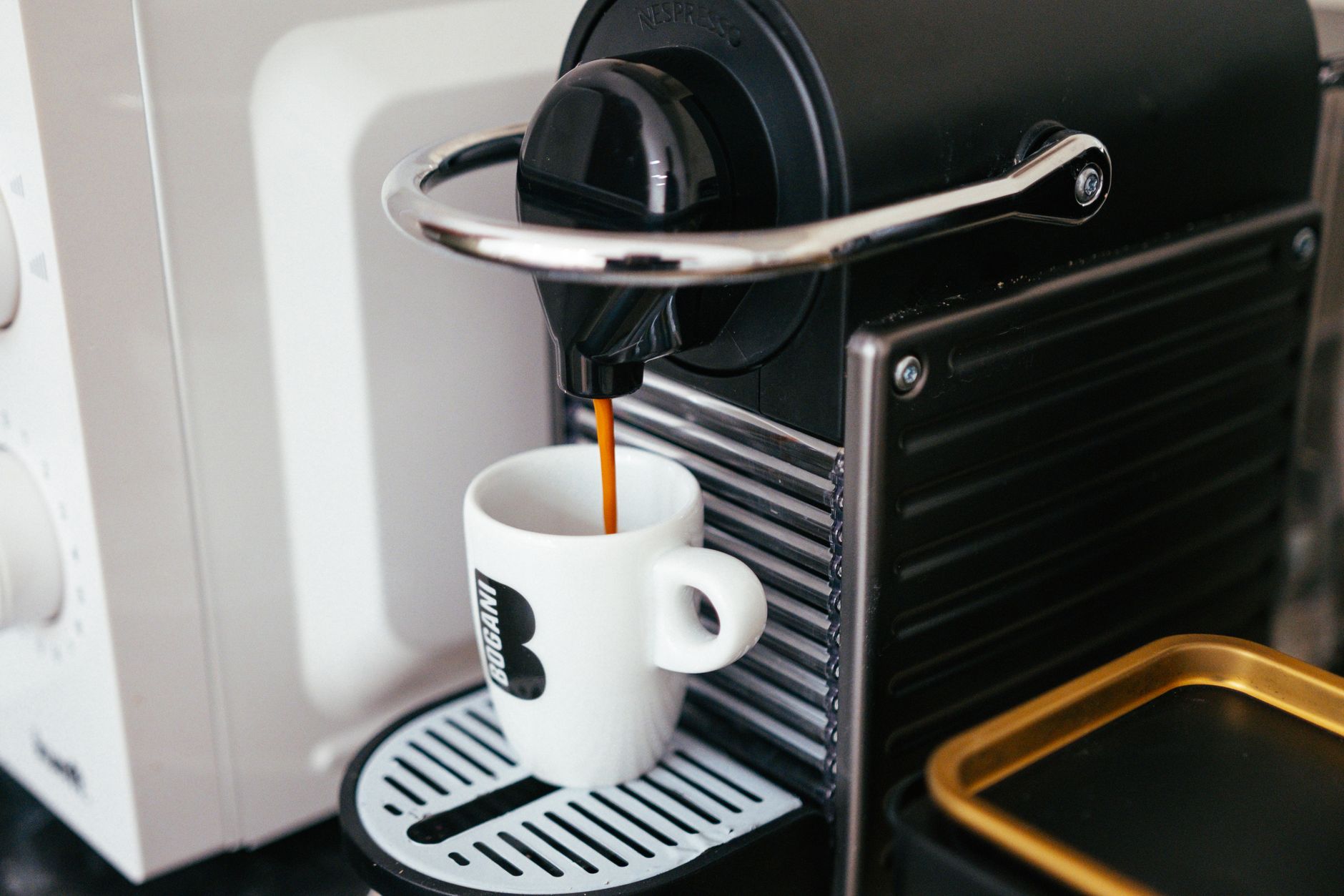 Close-up of a modern coffee machine brewing espresso into a branded mug indoors.