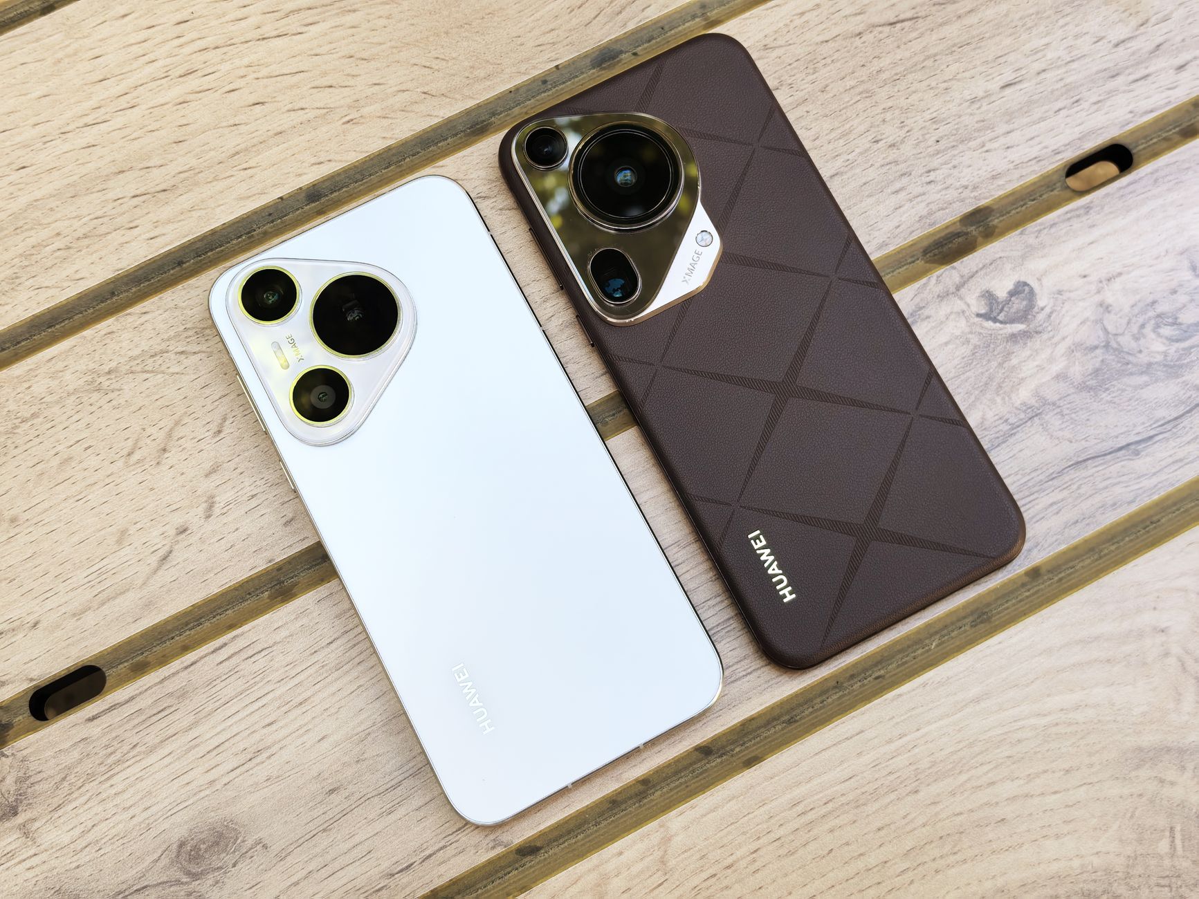 Two Huawei smartphones with sleek designs placed on a wooden table enhance the modern tech aesthetic.