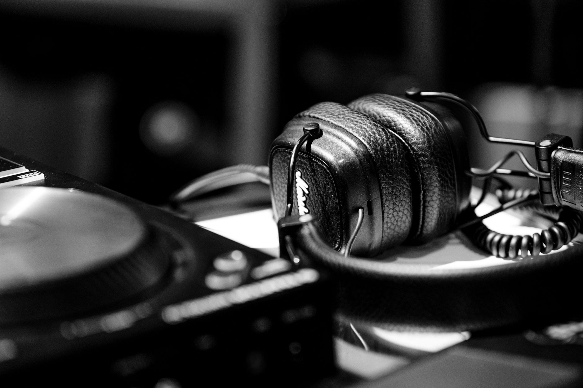 Close-up of DJ headphones and turntable in a studio setting, highlighting modern music equipment.