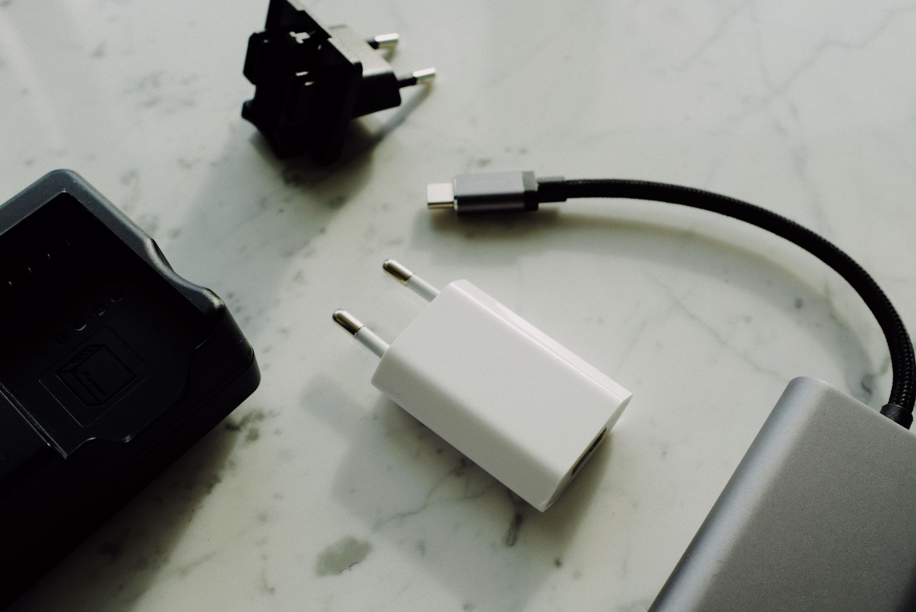 Set of various modern charging unit with adapter and small external battery pack with short cable placed on white marble table