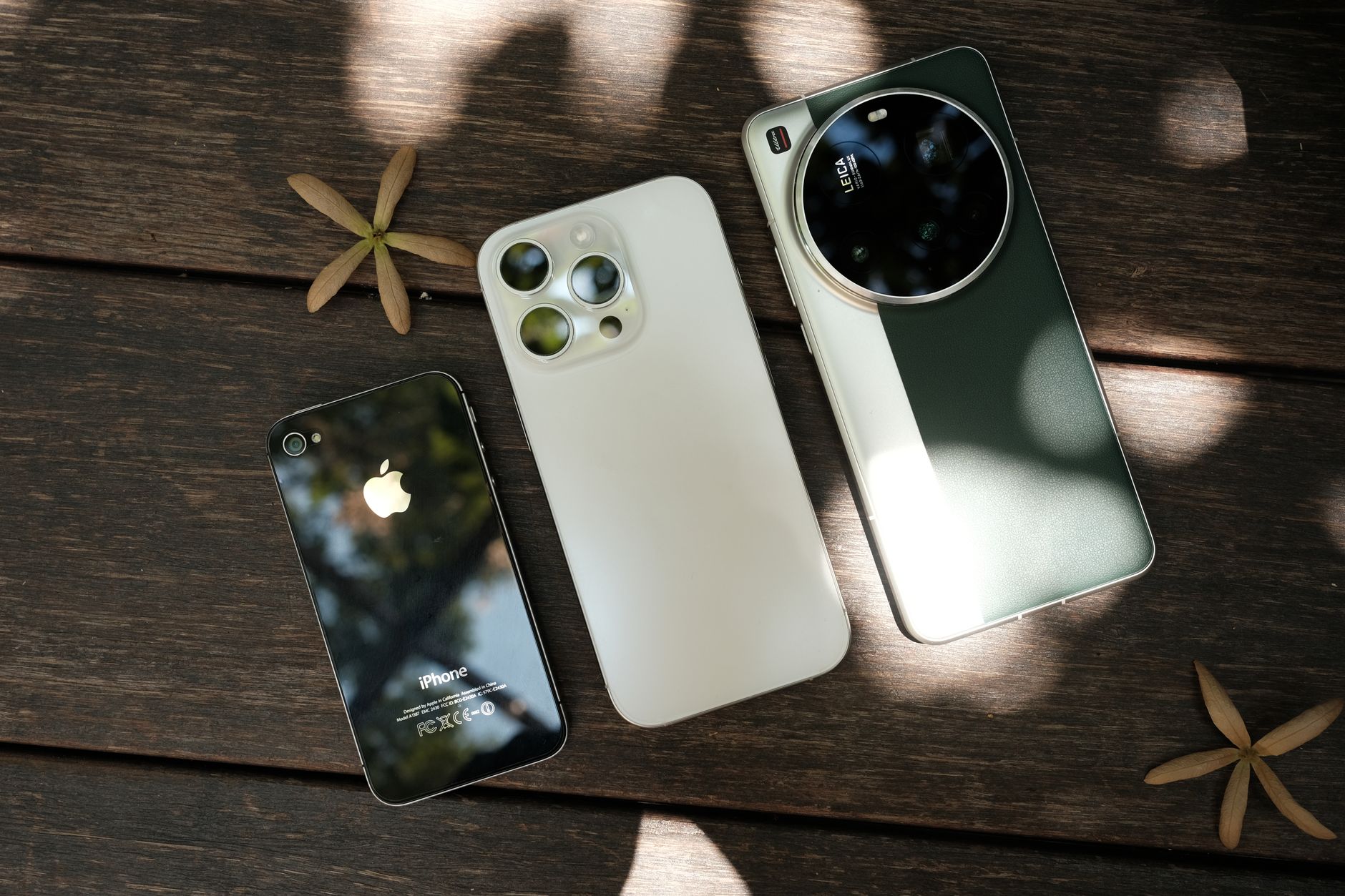 A trio of contemporary smartphones placed on a wooden table, showcasing different designs and features.