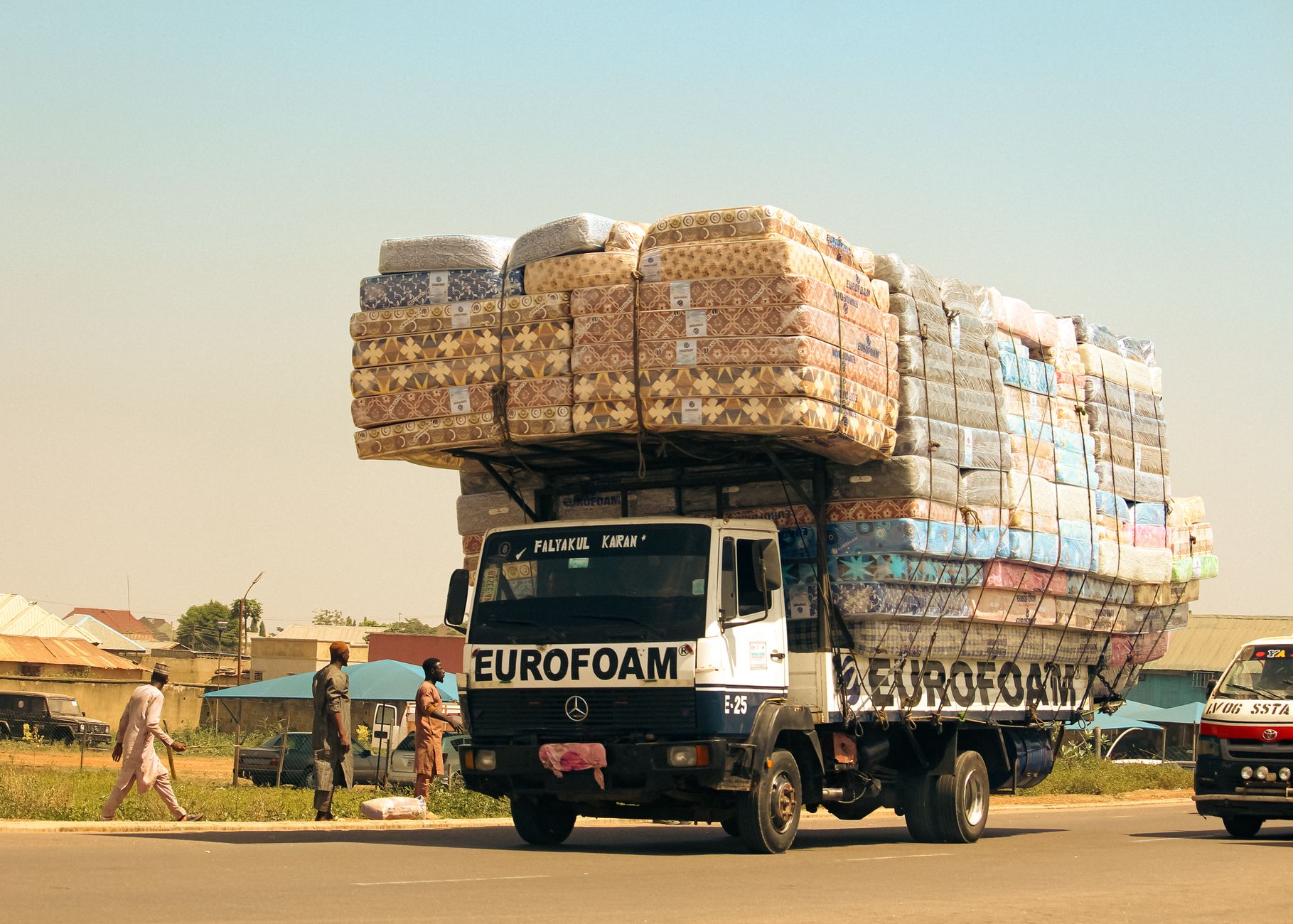 Truck loaded with Eurofoam mattresses on an urban street, showcasing innovative transport and commerce.