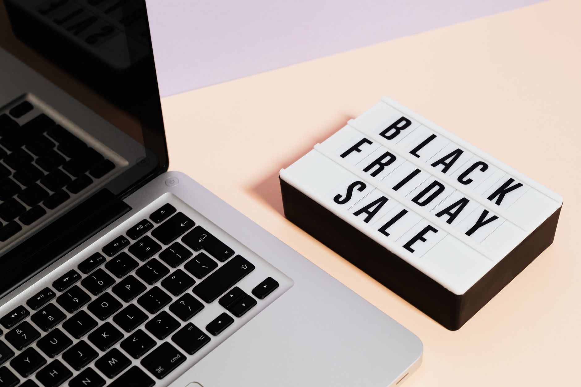 A laptop beside a lightbox sign with 'Black Friday Sale' for online shopping promotions.